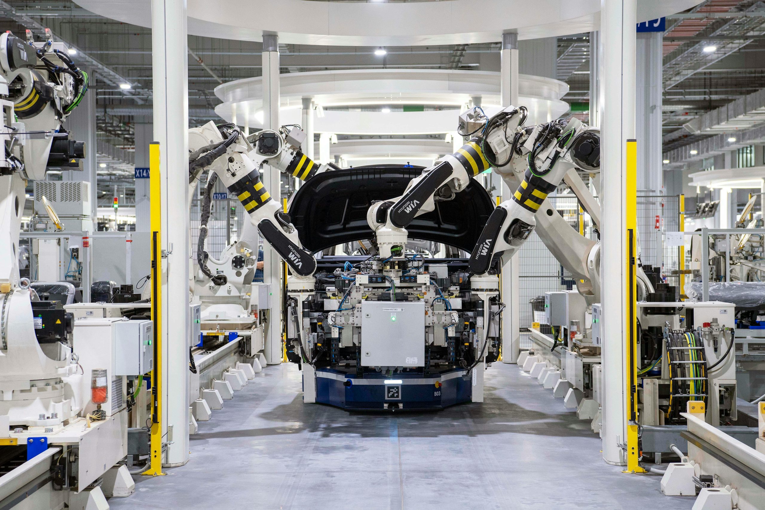 Factory robots with robotic arms assemble automobile parts on a production line.