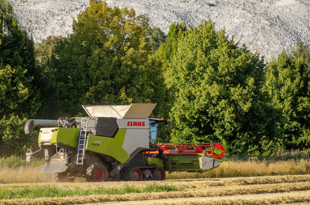 An automated machine harvesting crops in a large field, highlighting the efficiency of modern agricultural equipment.